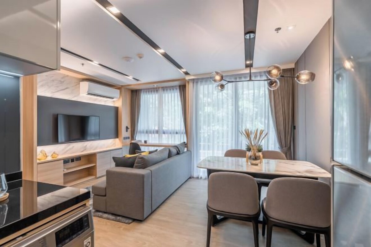 Een moderne woonkamer met een bank, televisie en een eethoek.