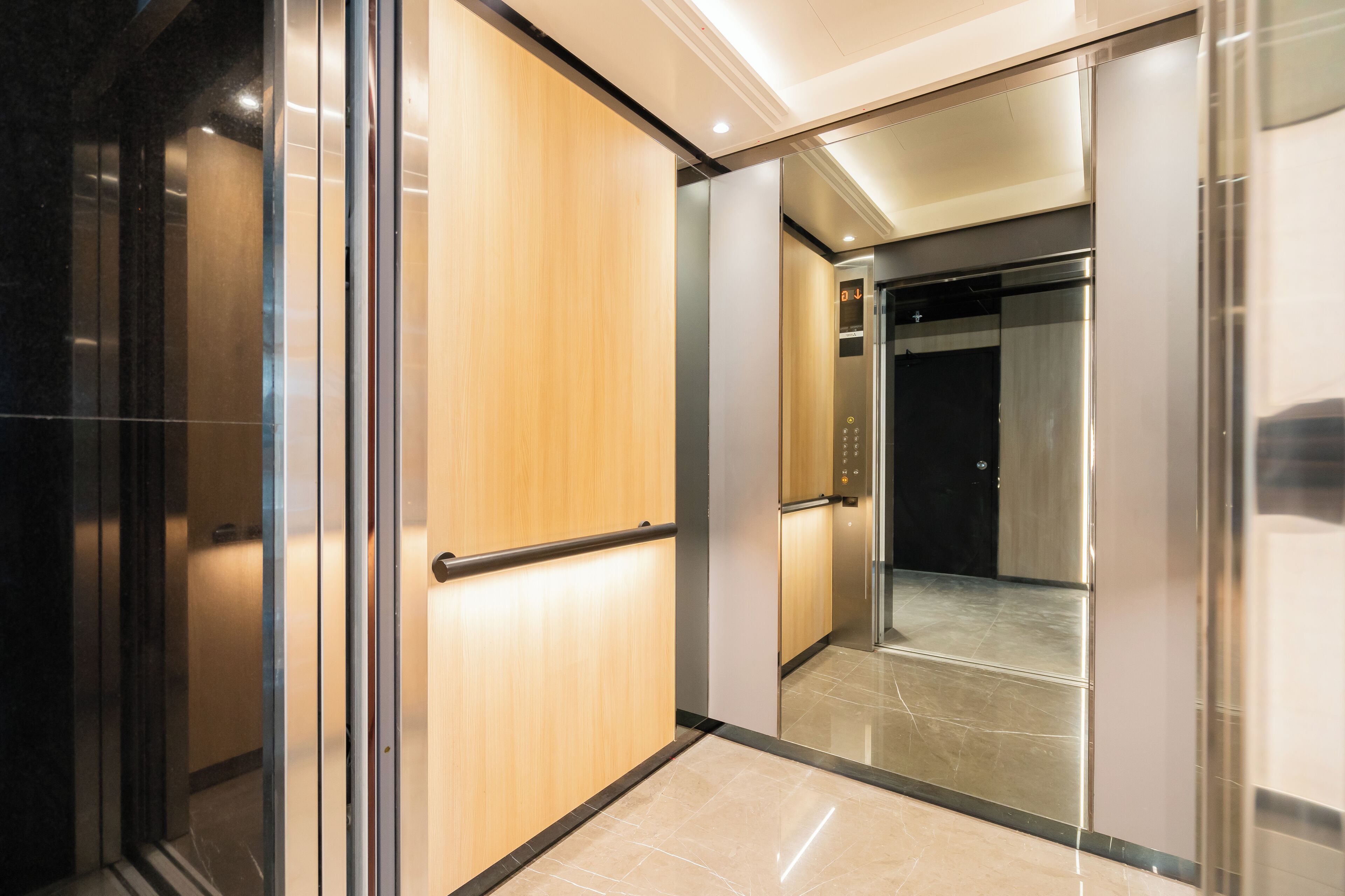 An interior view of a modern elevator with wooden paneling and a metallic finish.