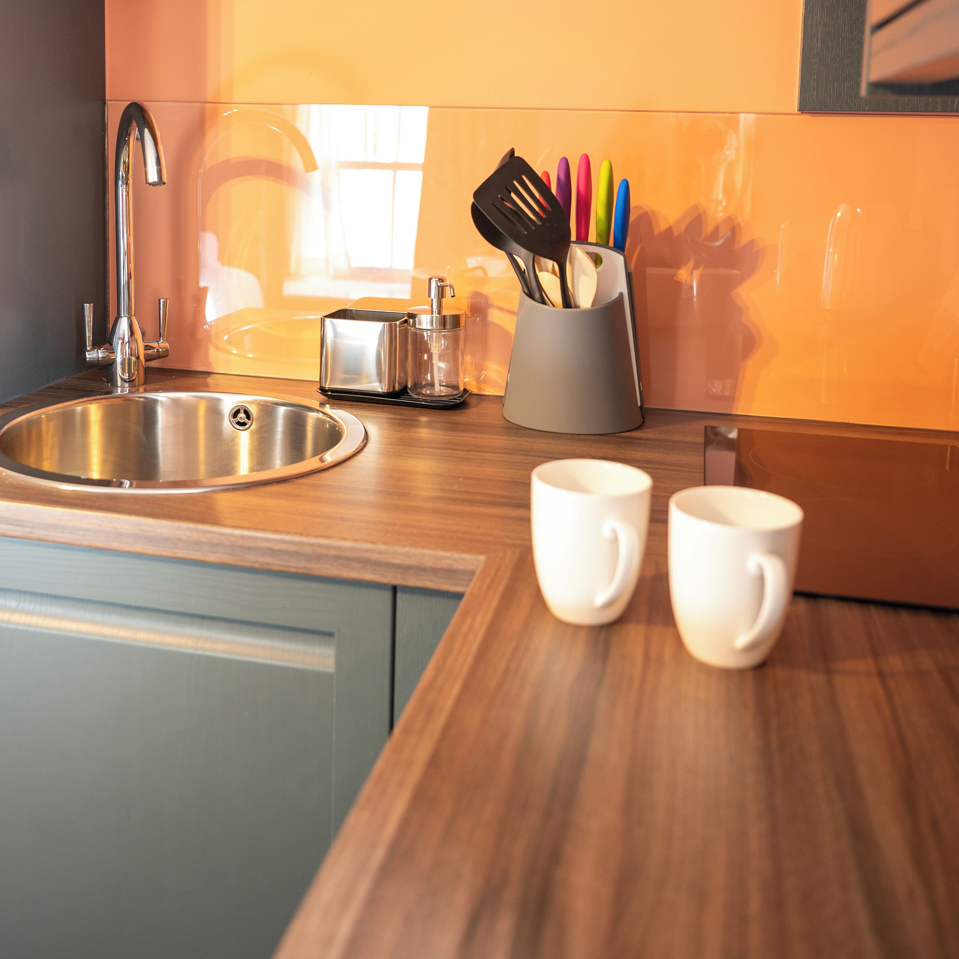 A modern kitchen with a stainless steel sink, a toaster, and a utensil holder on the counter.