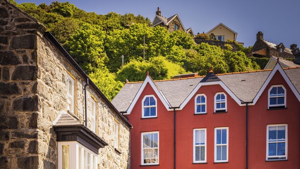 A traditional stone building with a red facade, a covered outdoor seating area with tables and chairs, and a staircase leading to the entrance. - The Fanny Talbot  (Barmouth)