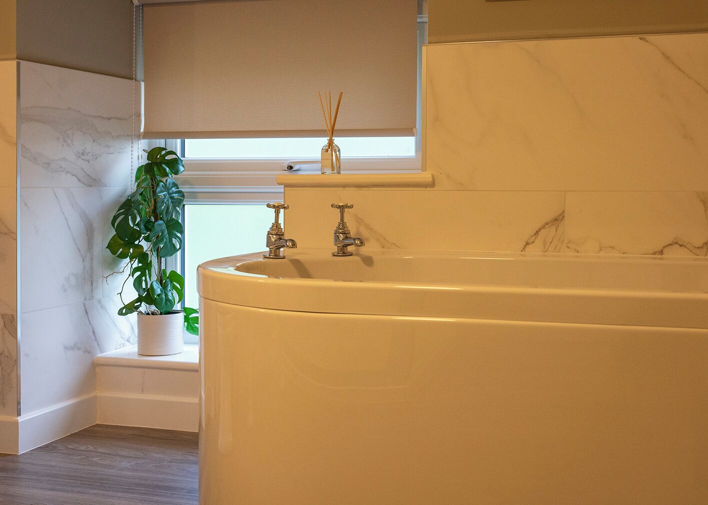 Un bagno con un lavandino in marmo, una pianta in vaso e una finestra con vista.