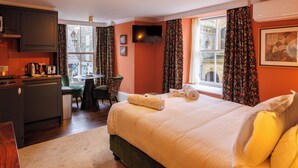 A hotel room with a bed, a desk, a chair, a TV, and a window with curtains. - The Fanny Talbot  (Barmouth)