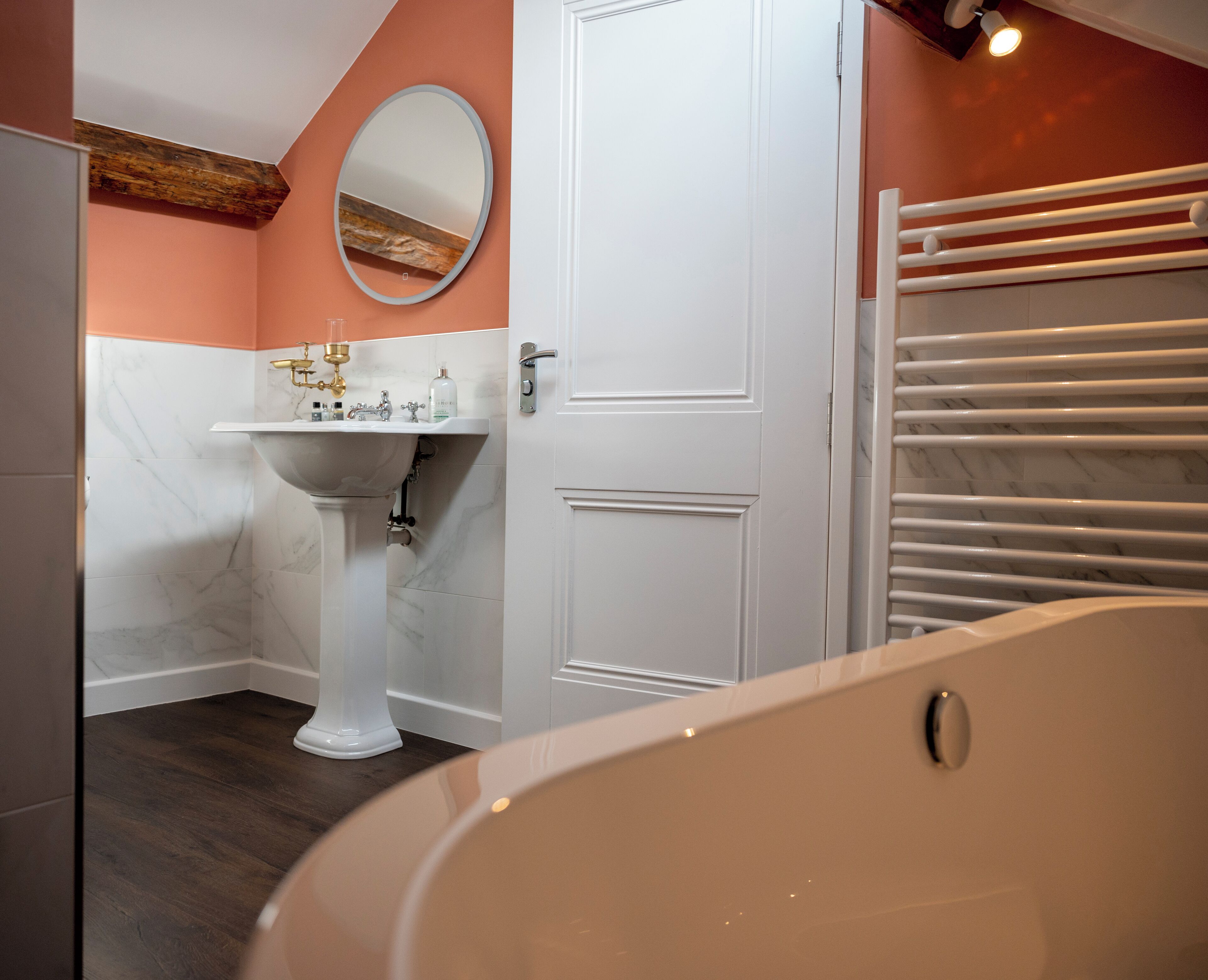 A bathroom with a white sink, a mirror, a bathtub, and a towel rack.