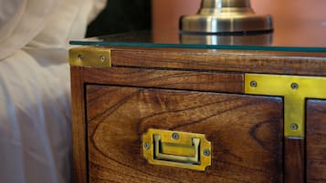 Un comodino in legno con dettagli in ottone e un piano in vetro, affiancato da una lampada bianca.