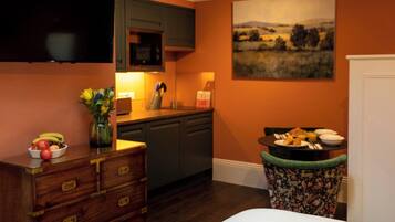 Habitación de hotel con cama, cómoda, televisor de pantalla plana, un cuadro y una kitchenette.