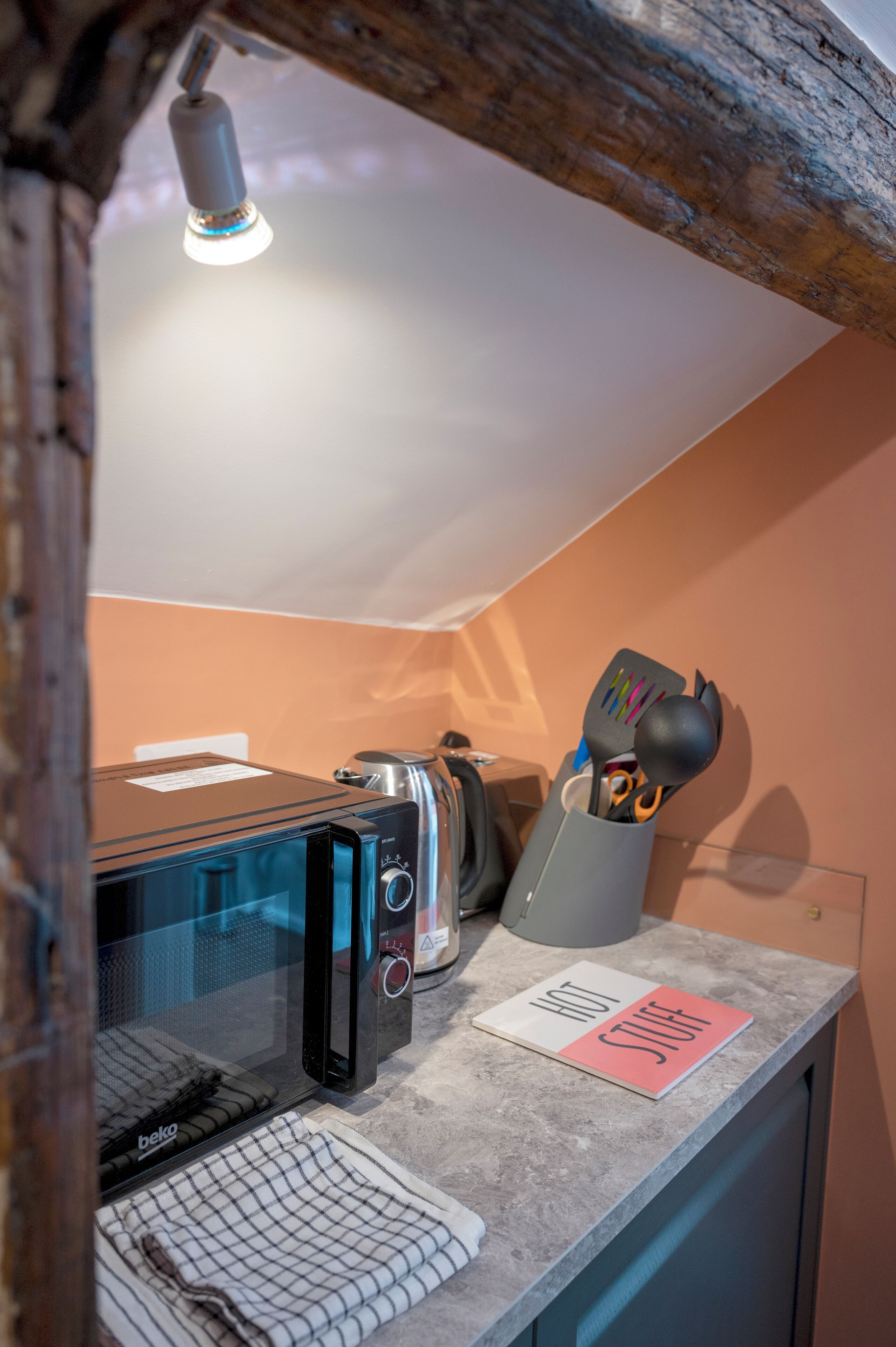 A kitchenette with a microwave, toaster, and a utensil holder on the counter.