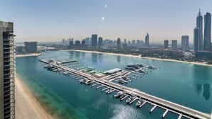 Uma marina com barcos atracados, um cais e o horizonte da cidade ao fundo.