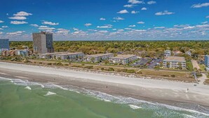 Een kusthotel met meerdere gebouwen, een strand en een heldere lucht.