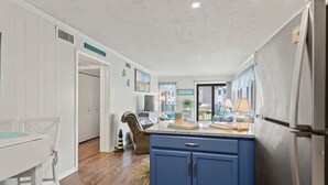 Een keuken met een blauwe kast, een witte eettafel en een koelkast.