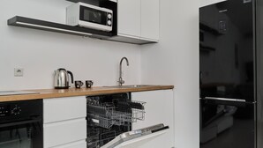 A modern kitchen with a dishwasher, oven, microwave, and black refrigerator.
