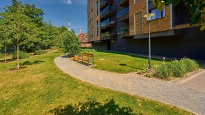 A modern apartment building with a grassy courtyard, a bench, and a pathway.