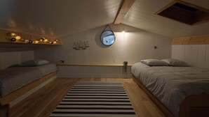 Un dormitorio acogedor en el ático con dos camas, un tapete a rayas y un tragaluz.