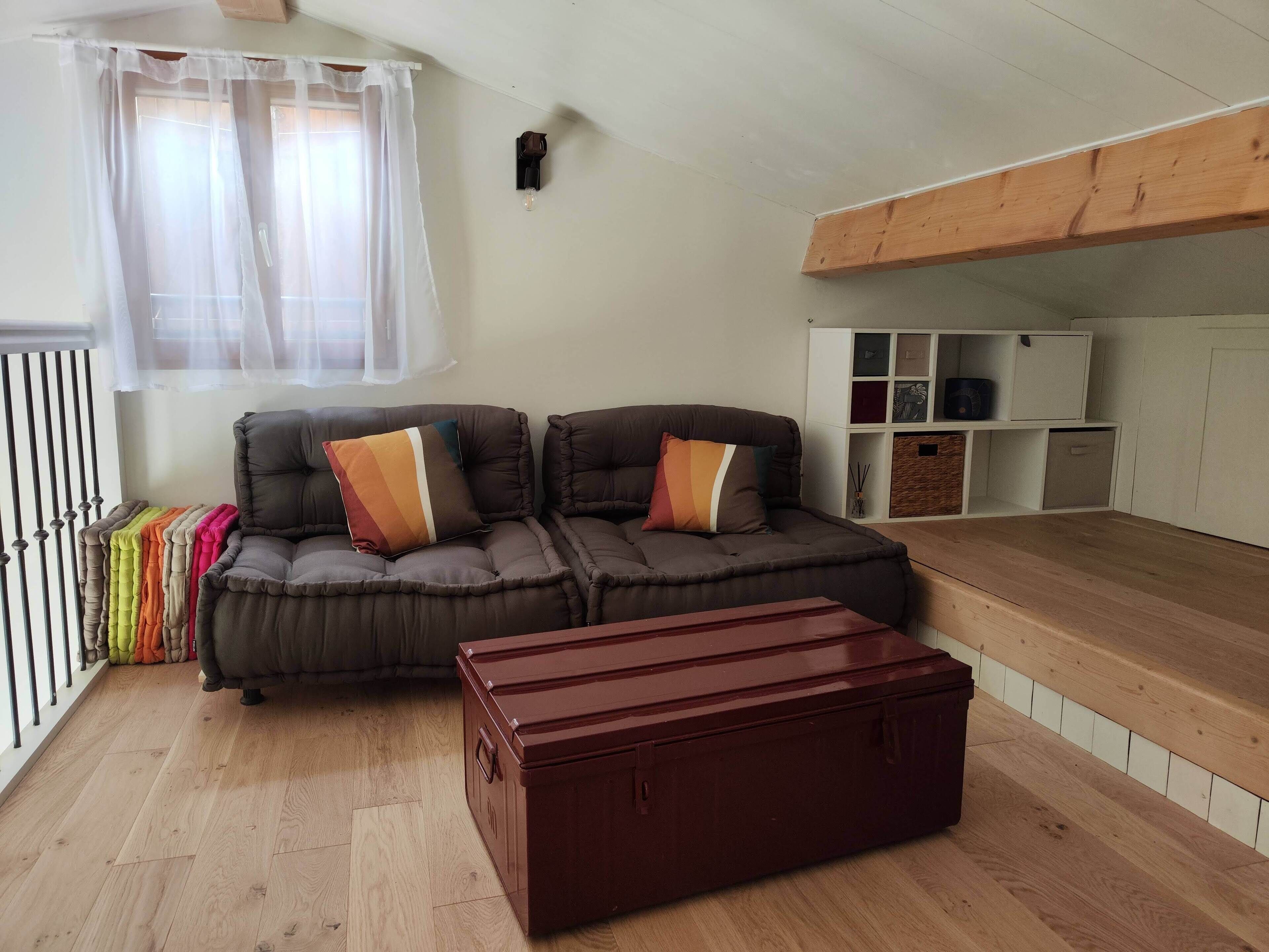 A cozy living room with a brown leather sofa, a wooden coffee table, and a white shelving unit.