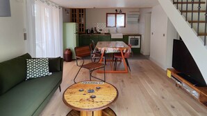 Amplia sala de estar con techo alto, una mesa de comedor, un sofá y una escalera que conduce a un nivel superior.