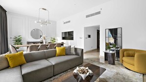 Ein modernes Wohnzimmer mit grauem Sofa, gelben Kissen, einem Couchtisch und einem gelben Sessel.