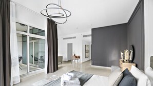 Ein modernes Schlafzimmer mit einem großen Bett, einem Schreibtisch und Blick auf einen Balkon.
