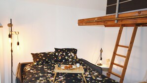 Une chambre à coucher avec un lit, une table de chevet, une lampe et une échelle.