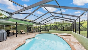 An indoor swimming pool with a covered patio area, including seating and a hot tub.