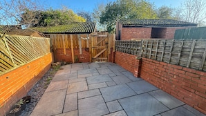 A paved patio with a wooden gate and brick walls. - a Quiet Semi Rural Property Located in Bolsover (Chesterfield)