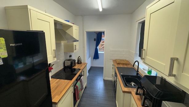 A compact kitchen with a black refrigerator, a toaster, a sink, and a stove. - a Quiet Semi Rural Property Located in Bolsover (Chesterfield)