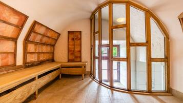 Una habitación con un banco de madera, un ventanal con marco de madera y un banco con respaldo de listones.