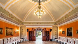 Ein prachtvoller Saal mit hoher Decke, aufwendigen Kronleuchtern und Reihen weißer Stühle.