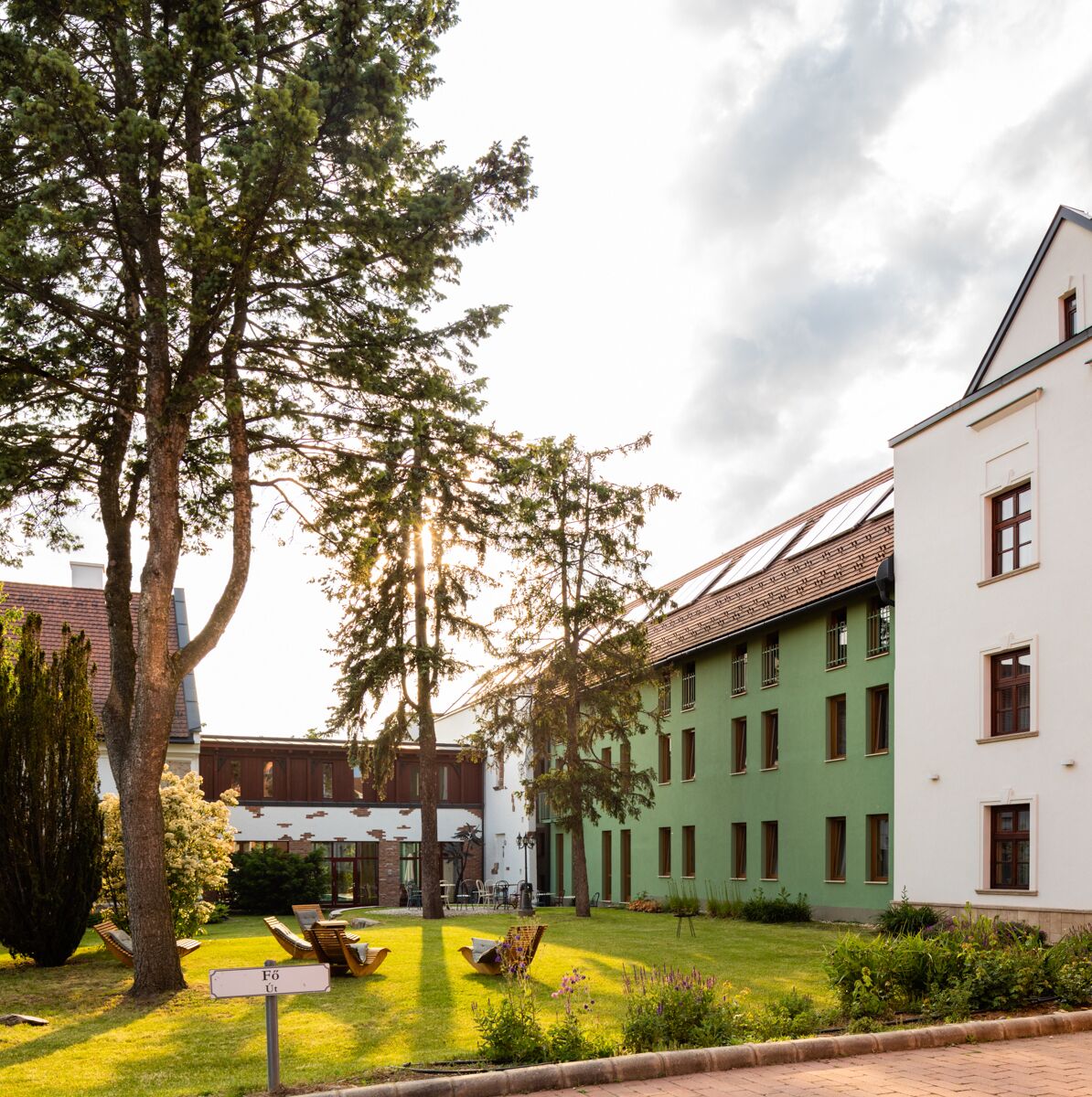 A courtyard with a lawn, outdoor seating, and buildings with green and white facades.