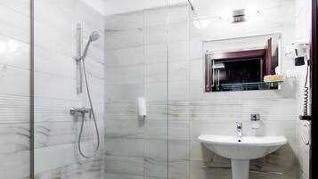 A modern bathroom with a glass shower enclosure, a white sink, and a toilet.