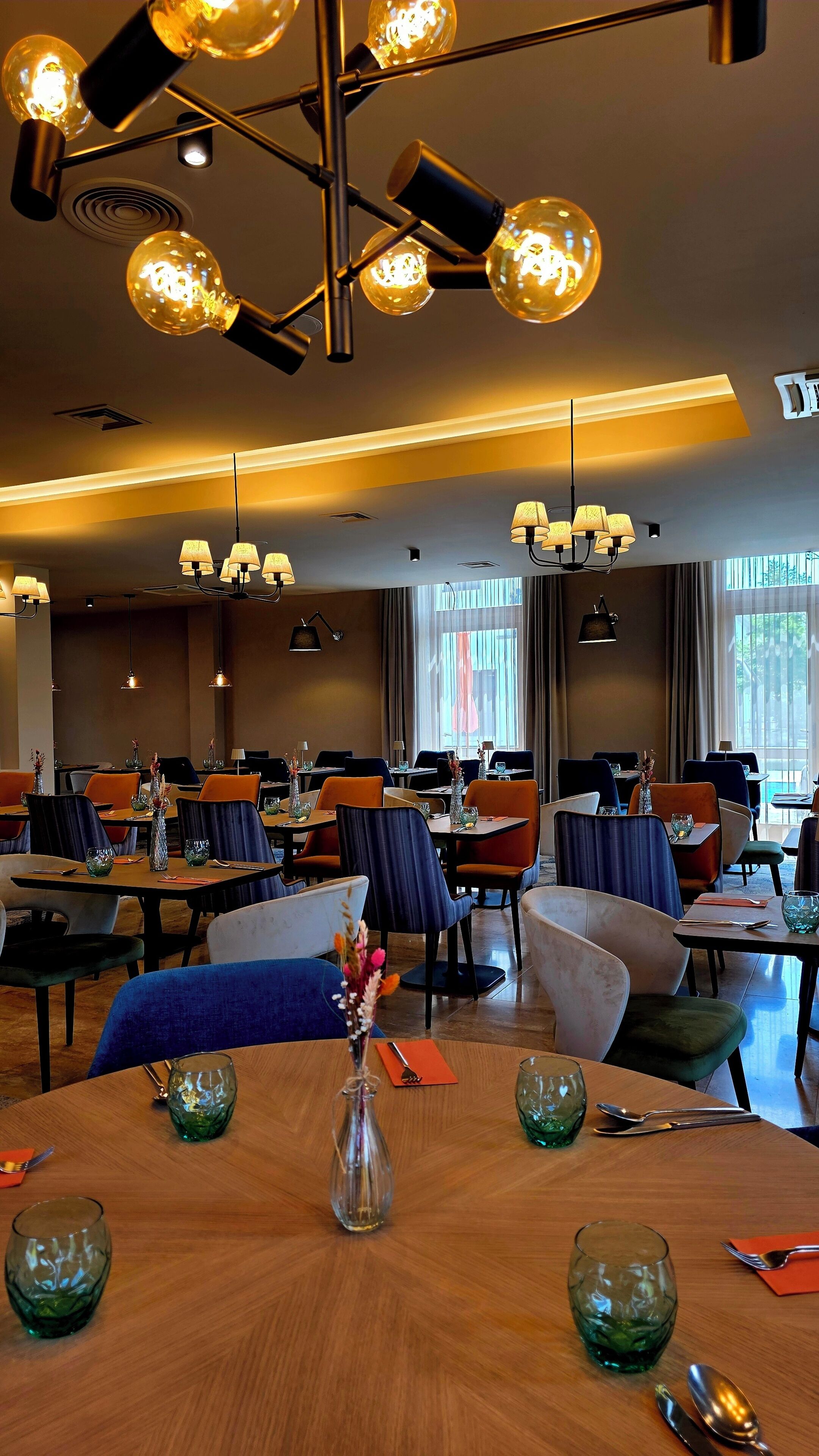 Un restaurante con mesas redondas, sillas e iluminación colgante.
