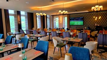 A restaurant with multiple tables, chairs, and a television screen.