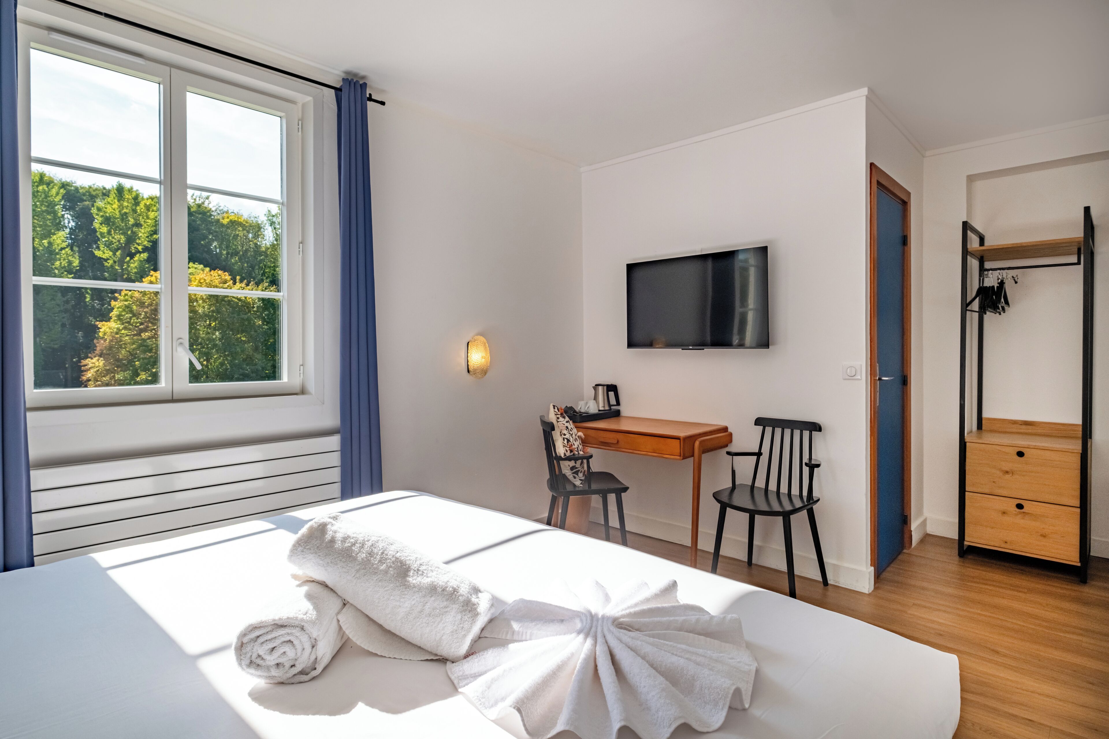 Een slaapkamer met een bed, bureau, stoel, televisie en een kledingkast.