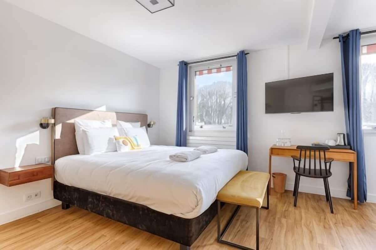 Ein Schlafzimmer mit Bett, Nachttisch, Schreibtisch, Stuhl und einem an der Wand befestigten Fernseher.