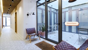 Un intérieur moderne avec un banc, une plante en pot et une porte vitrée donnant sur un espace extérieur.