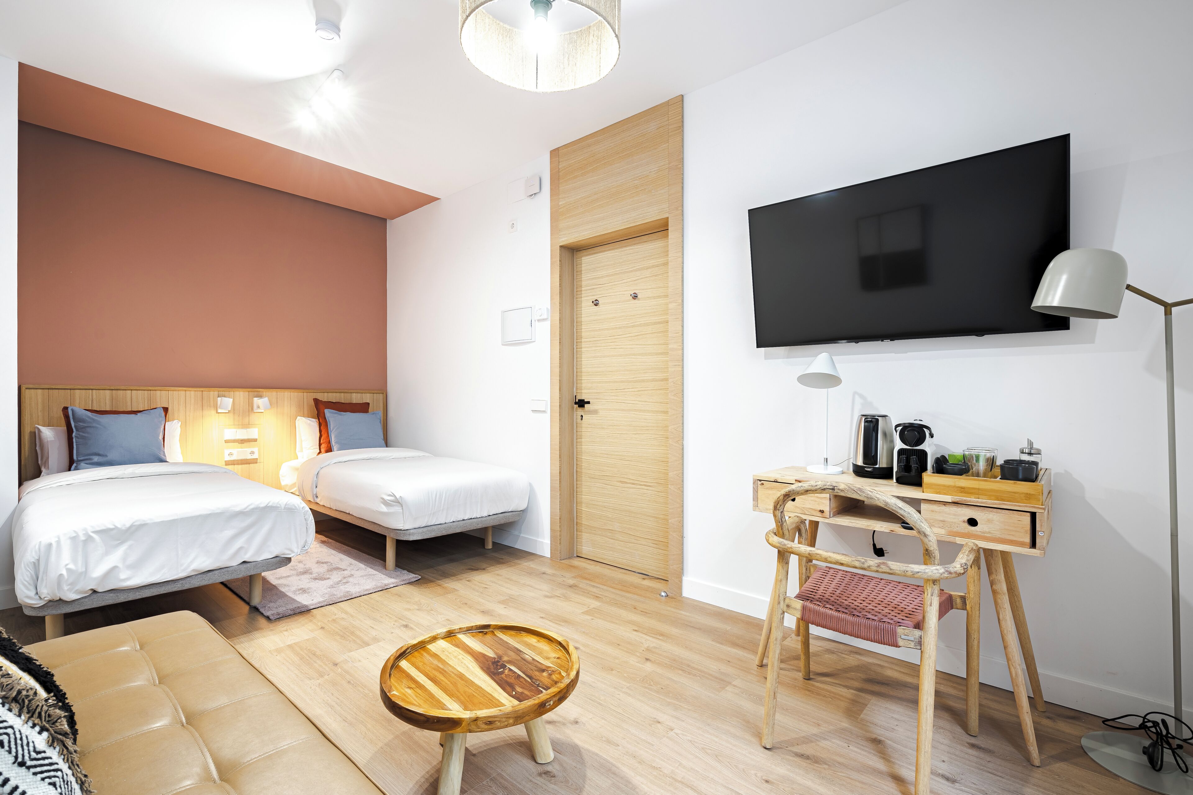 Een moderne hotelkamer met twee bedden, een bureau met stoel, een televisie en een lamp.