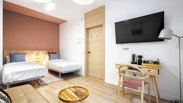 Een moderne hotelkamer met twee bedden, een bureau met stoel, een televisie en een lamp.
