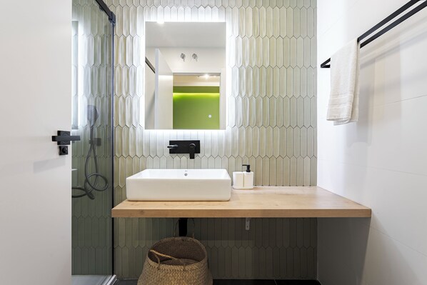 Un baño moderno con un lavamanos blanco, un espejo y un perchero para toallas.