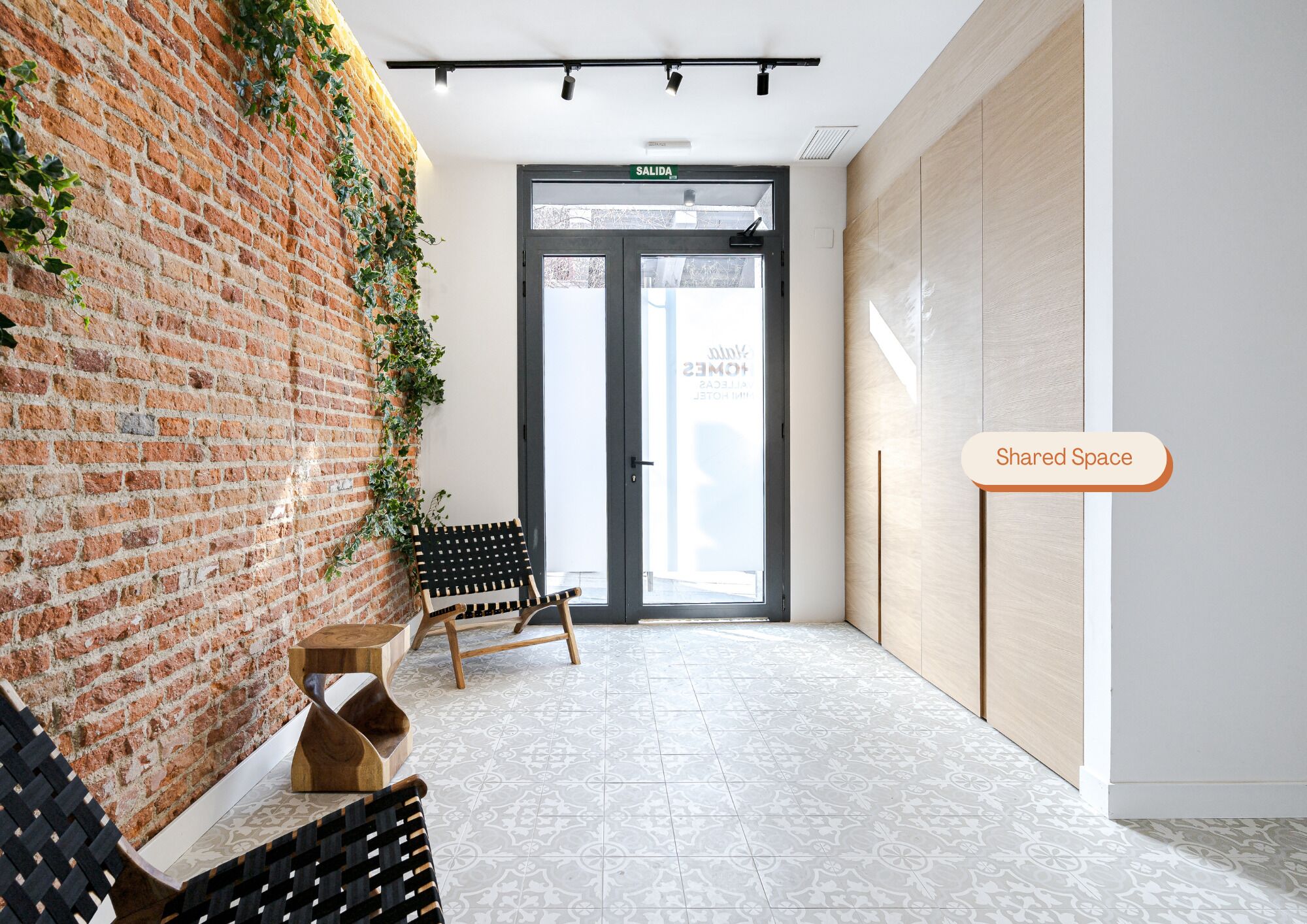 Un interior moderno con una pared de ladrillo, un banco, una silla de madera y una puerta que dice "SALIDA".