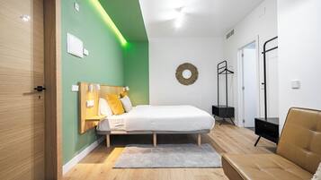 Un dormitorio moderno con cama, armario de madera, alfombra gris y sofá de cuero marrón.
