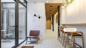 Un intérieur moderne avec une porte vitrée donnant sur l’extérieur, un sol à motifs et un panneau indiquant « Espace partagé ».