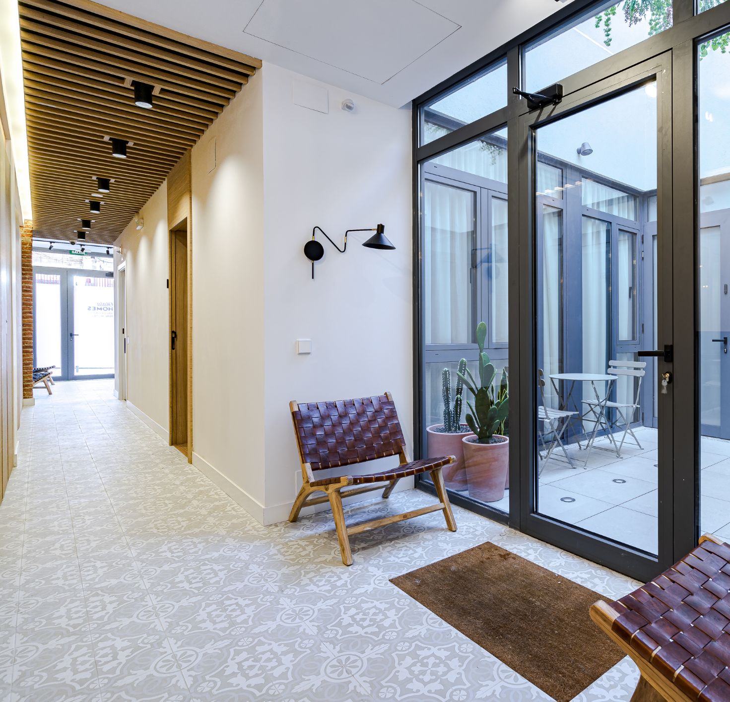 Ein modernes Interieur mit einer Sitzbank, einem Blumentopf und einer Glastür, die zu einem Außenbereich führt.