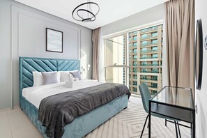 Een moderne slaapkamer met een groot bed, een glazen tafel en uitzicht op een hoog gebouw.