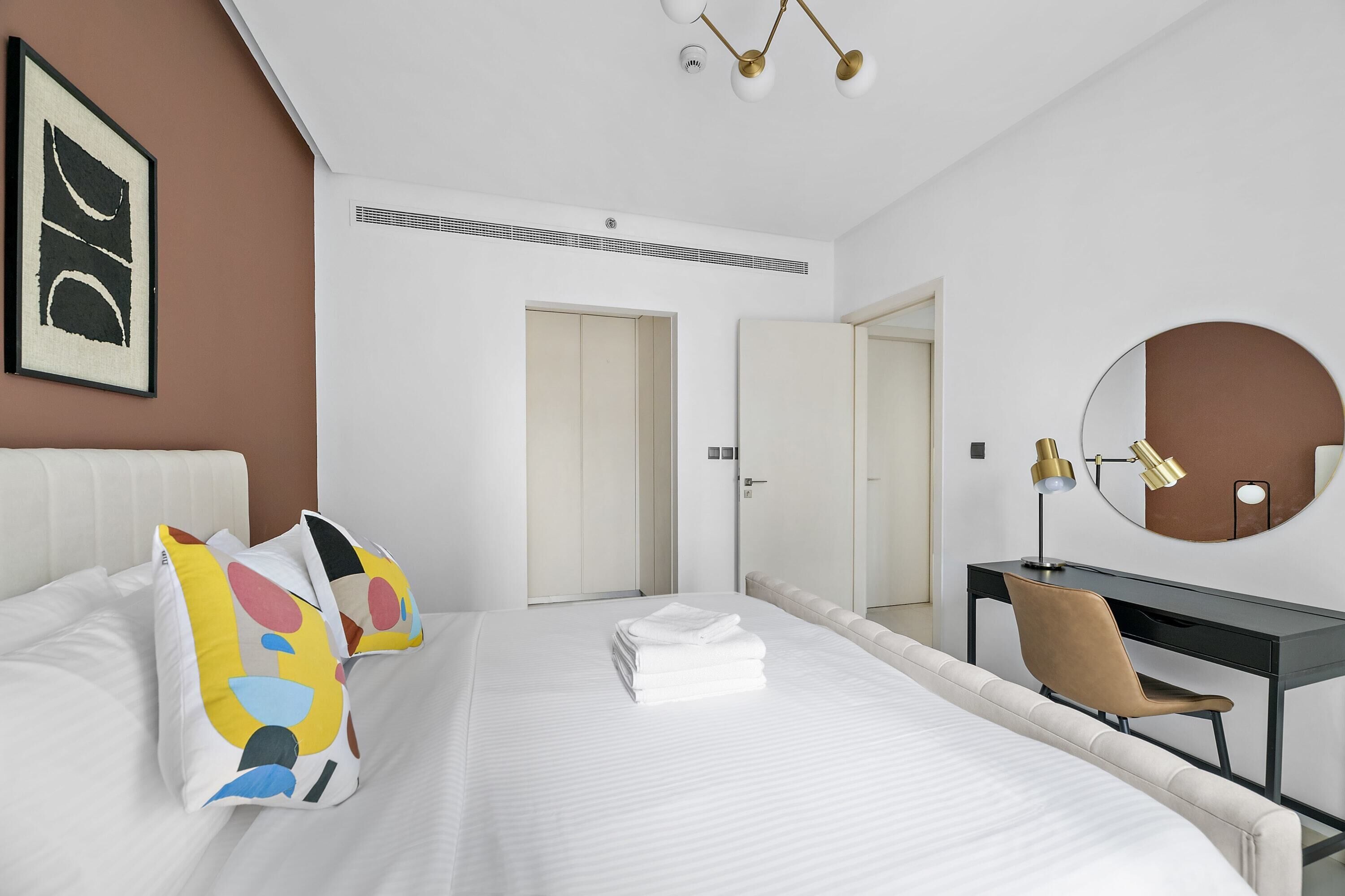 Een moderne hotelkamer met een groot bed, een bureau, een stoel en een spiegel.