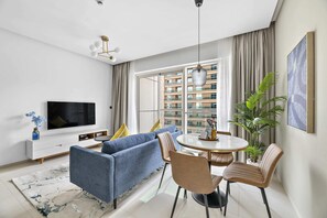 Een moderne woonkamer met een bank, stoelen, een televisie en een eettafel.