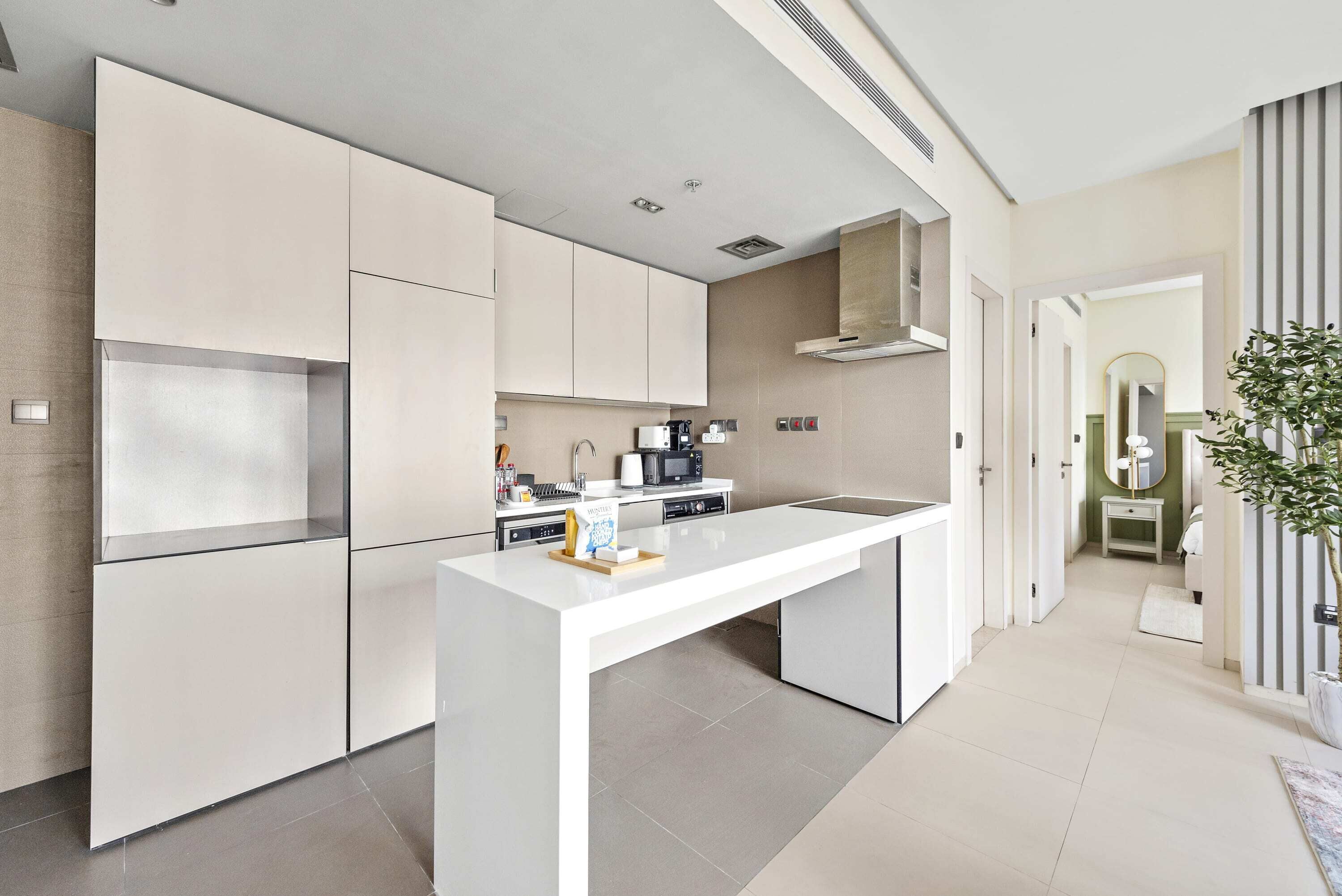A modern kitchen with white cabinetry, a central island, and a built-in microwave.