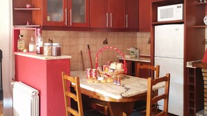 A kitchen with wooden cabinets, a microwave, a refrigerator, a dining table with chairs, and a radiator.