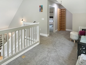 A carpeted hallway with a white railing, a closet with a wooden ladder, and a small white stool. - Mountain-view cabin with hot tub, game room, and 3 bedrooms. Free rafting, train, zip (Bryson City)