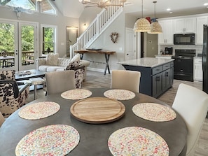 A modern kitchen with white cabinets, a black refrigerator, and a dining area with a round table and chairs. - Mountain-view cabin with hot tub, game room, and 3 bedrooms. Free rafting, train, zip (Bryson City)