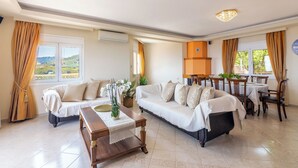 A spacious living area with two sofas, a wooden coffee table, and a dining table with chairs. - Nami Villa SeaView | Private Pool  (Heraklion)