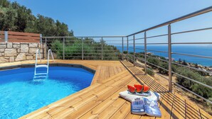 A wooden deck with a swimming pool, a metal railing, and a view of the sea. - Nami Villa SeaView | Private Pool  (Heraklion)
