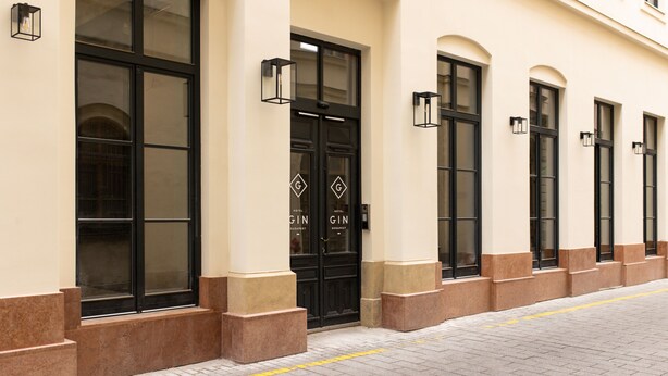 A hotel entrance with large windows, black doors, and a yellow tactile paving strip. - Hotel GIN Budapest (Budapest)